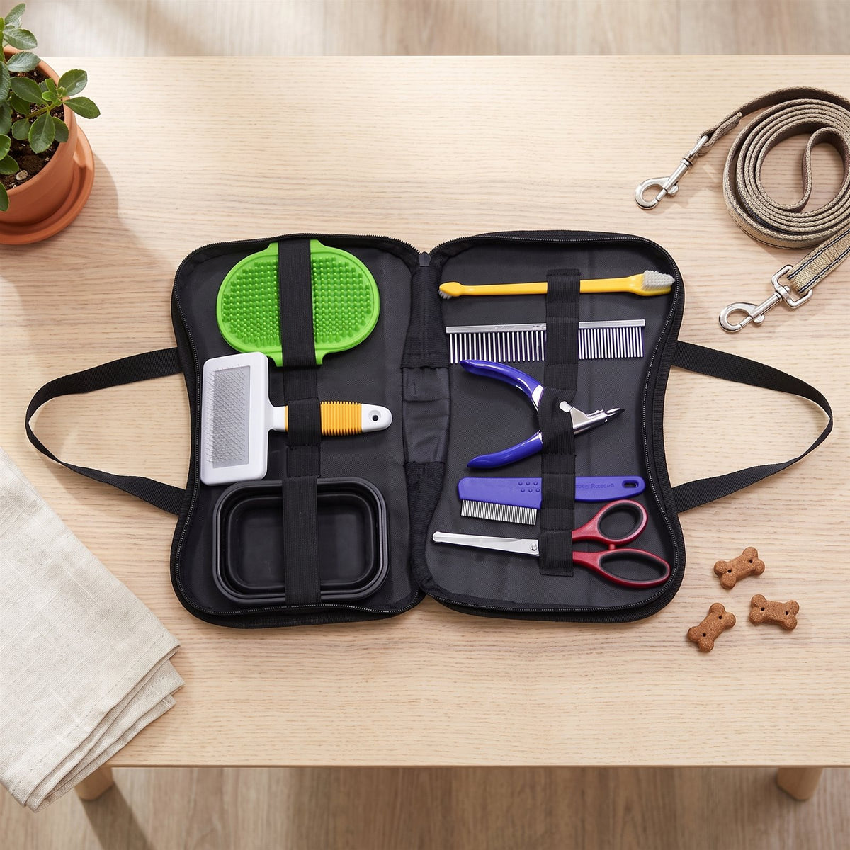Open zip case with slicker brush, rubber brush, combs, nail clipper, scissors, toothbrush and travel bowl