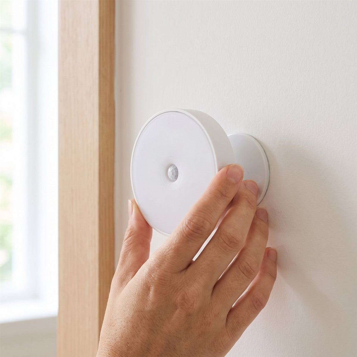 Hand attaching the puck light to its magnetic adhesive mount, no tools